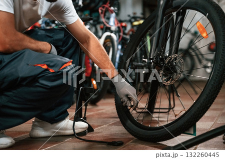 Inflates a tire with hand pump. Close up view of man's hands that is repairing bicycle 132260445