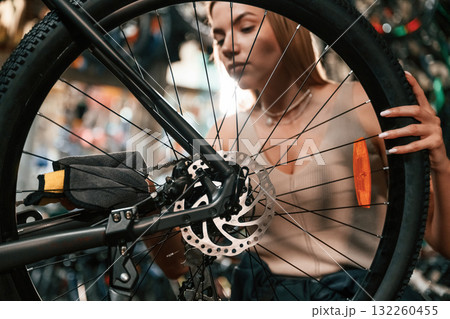 Taking care of the wheel. Repair woman in bicycle shop, working in store 132260455