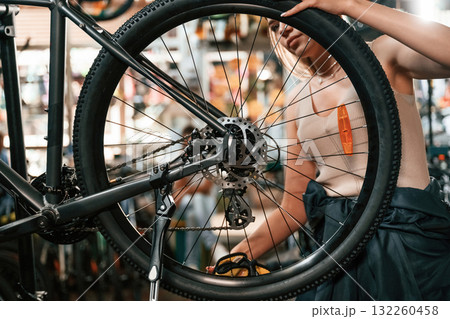 Making it clean. Repair woman in bicycle shop, working in store Making it clean. Repair woman in bicycle shop, working in store 132260458