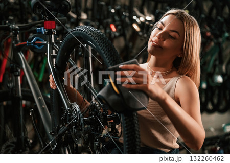 Back wheel, taking care of it. Repair woman in bicycle shop, working in store Back wheel, taking care of it. Repair woman in bicycle shop, working in store 132260462