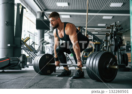 Lifts a barbell. Strong muscular man is working out in the gym Lifts a barbell. Strong muscular man is working out in the gym 132260501