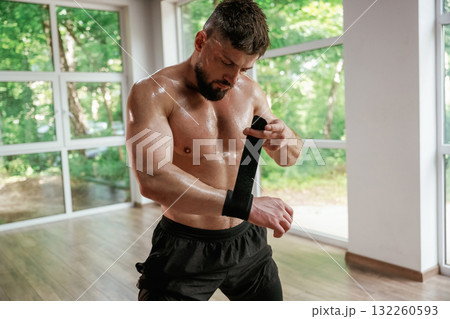 Wearing the protective bandage on hands. Strong muscular man is working out in the gym Wearing the protective bandage on hands. Strong muscular man is working out in the gym 132260593