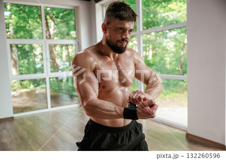 Wearing the protective bandage on hands. Strong muscular man is working out in the gym 132260596