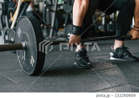 Big and heavy barbell in hands. Strong muscular man is working out in the gym Big and heavy barbell in hands. Strong muscular man is working out in the gym 132260609