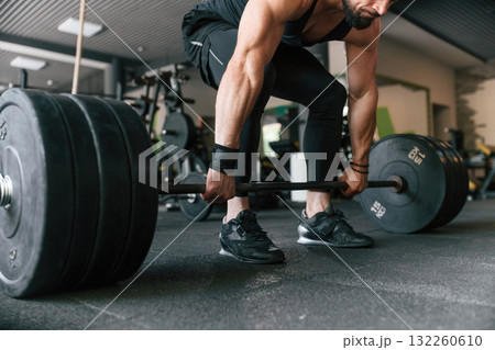 Big and heavy barbell in hands. Strong muscular man is working out in the gym 132260610