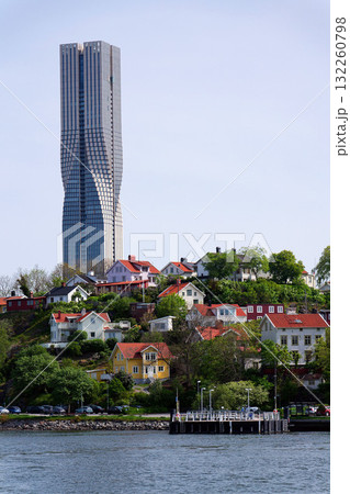 Colony of small wooden historic houses on the Slottsberget mountain with the tallest Scandinavian building Karlatornet skycraper in Lindholmen, Gothenburg, Sweden Colony of small wooden historic houses on the Slottsberget mountain with the tallest Scandinavian building Karlatornet skycraper in Lindholmen, Gothenburg, Sweden 132260798