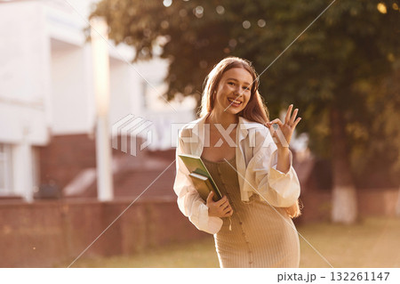 Standing, front view. Beautiful female student is outdoors near the university Standing, front view. Beautiful female student is outdoors near the university 132261147