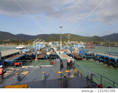 Ferry Docking at a Bustling Coastal Port with Mountain Views and Clear Skies 132261184