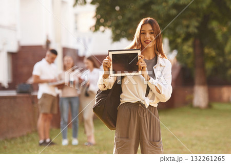 Woman is showing digital tablet, copy space. Group of students are outside together Woman is showing digital tablet, copy space. Group of students are outside together 132261265