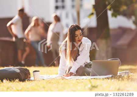 Sunbeam is illuminating the woman. Group of students are outside together 132261289