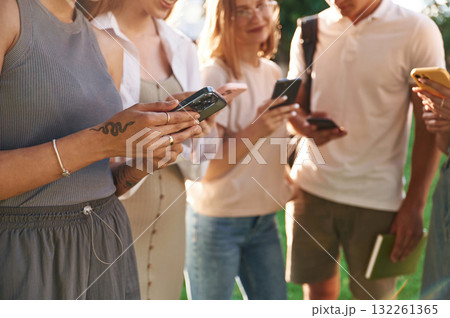 Bunch of smartphones. Group of students are outside together Bunch of smartphones. Group of students are outside together 132261365