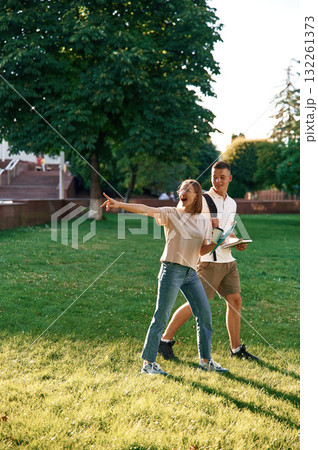 Showing something by finger. Two students are together outdoors Showing something by finger. Two students are together outdoors 132261373