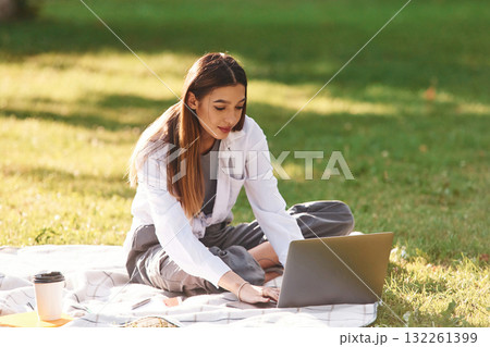 Silver colored laptop, sitting. Beautiful female student is outdoors near the university 132261399