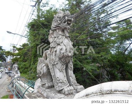 Intricate Stone Dragon Sculpture on a Wall Overlooking a Street with Tangled Wires 132261512