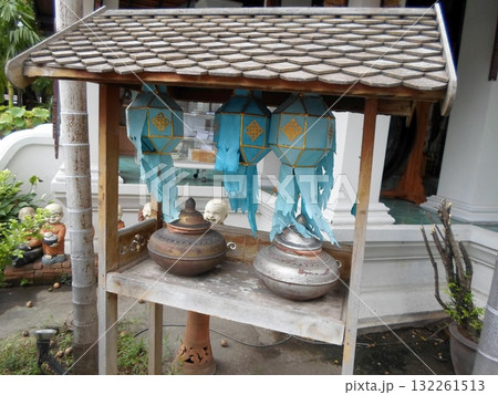 Wooden Shrine Shelf with Blue Lanterns and Metal Pots in a Lush Garden Setting 132261513