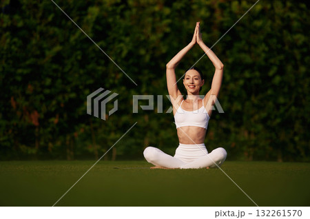 Doing yoga exercises. Attractive young fitness woman is on the green grass at daytime Doing yoga exercises. Attractive young fitness woman is on the green grass at daytime 132261570