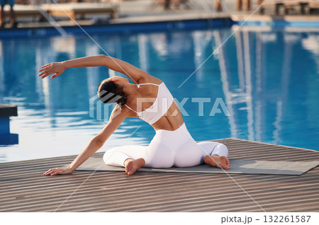 Stretching exercises. Fitness woman is near the pool Stretching exercises. Fitness woman is near the pool 132261587