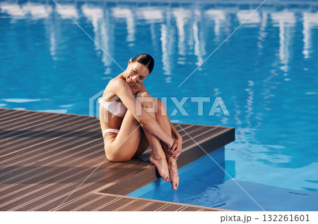 Enjoying the vacation. Beautiful woman in bikini is resting by the pool 132261601