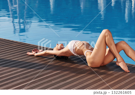 Lying down, close up view. Beautiful woman in bikini is resting by the pool 132261605