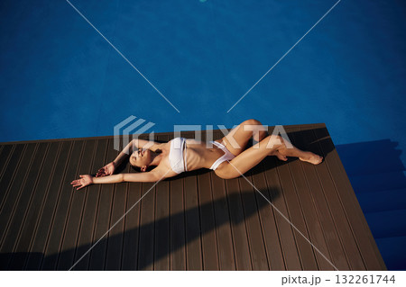 Near the water, rest. Beautiful woman in bikini is resting by the pool Near the water, rest. Beautiful woman in bikini is resting by the pool 132261744