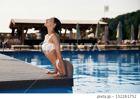 Positive vibes. Beautiful woman in bikini is resting by the pool Positive vibes. Beautiful woman in bikini is resting by the pool 132261752