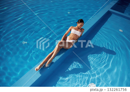 View from the top, lying down. Beautiful woman in bikini is resting by the pool View from the top, lying down. Beautiful woman in bikini is resting by the pool 132261756
