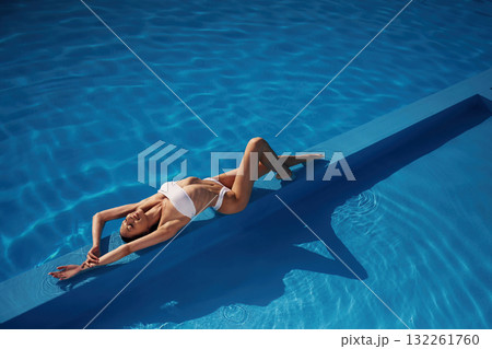 View from the top, lying down. Beautiful woman in bikini is resting by the pool View from the top, lying down. Beautiful woman in bikini is resting by the pool 132261760