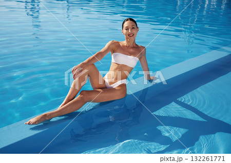 Conception of wellness. Beautiful woman in bikini is resting by the pool Conception of wellness. Beautiful woman in bikini is resting by the pool 132261771