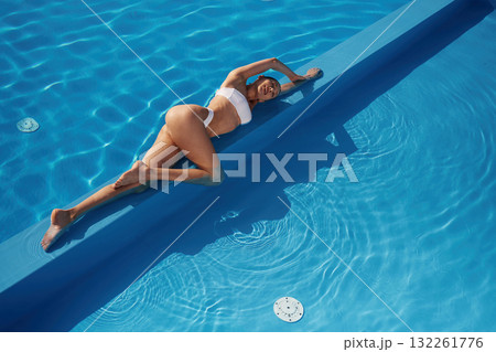 Conception of wellness. Beautiful woman in bikini is resting by the pool Conception of wellness. Beautiful woman in bikini is resting by the pool 132261776