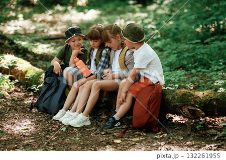 Sitting with camera and water bottle. Kids in forest at summer daytime together 132261955