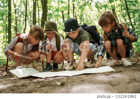 On the ground with map. Kids in forest at summer daytime together On the ground with map. Kids in forest at summer daytime together 132261962
