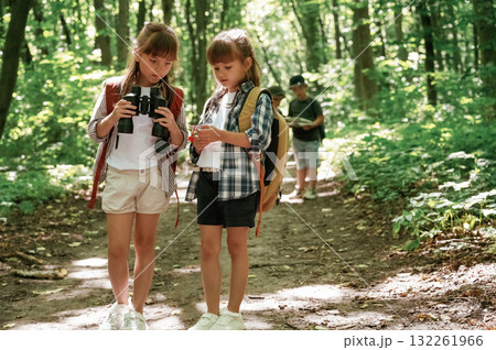 Using binoculars. Kids in forest at summer daytime together 132261966
