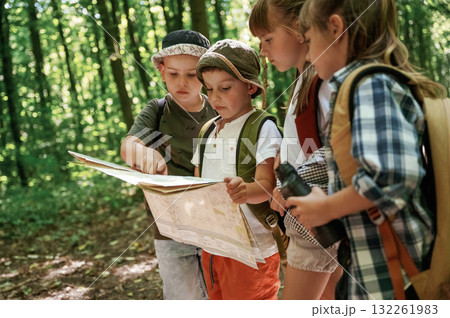 Smart boy is reading the map. Kids in forest at summer daytime together Smart boy is reading the map. Kids in forest at summer daytime together 132261983