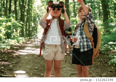 Using binoculars. Kids in forest at summer daytime together 132262149
