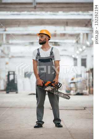 Saw in hands. Industrial worker in wooden warehouse 132262194