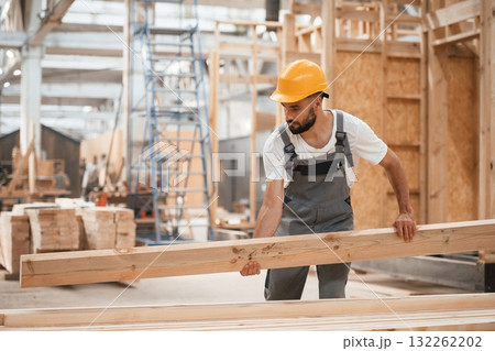 Carrying the plank. Industrial worker in wooden warehouse 132262202