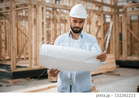 Architect is with plan of the building. Industrial worker in wooden warehouse 132262213