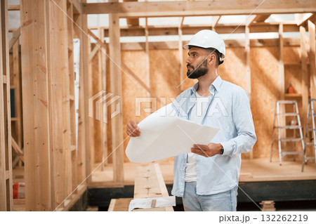 Architect is with plan of the building. Industrial worker in wooden warehouse 132262219