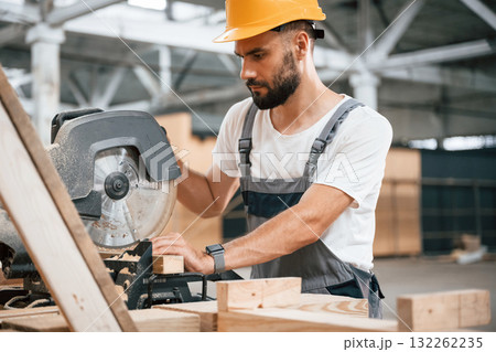 Side view, cutting the wood. Industrial worker in the warehouse 132262235