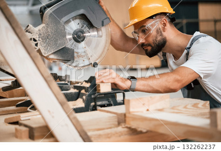 Side view, cutting the wood. Industrial worker in the warehouse 132262237