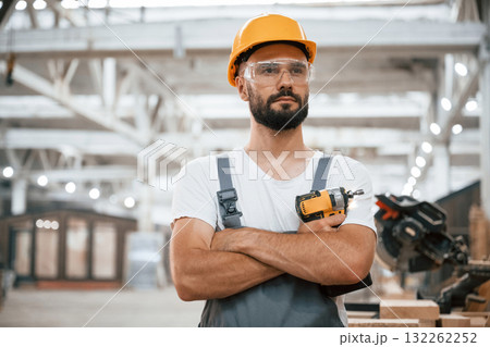 Cordless impact driver in hand. Industrial worker in wooden warehouse 132262252
