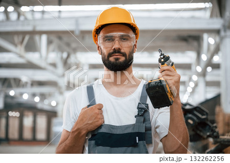 With cordless impact driver. Industrial worker in wooden warehouse With cordless impact driver. Industrial worker in wooden warehouse 132262256