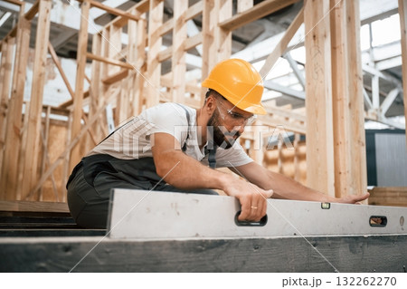 Checking the straight by using leveling tool. Industrial worker in wooden warehouse Checking the straight by using leveling tool. Industrial worker in wooden warehouse 132262270
