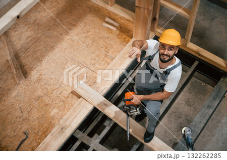 Saw in hands. Industrial worker in wooden warehouse 132262285