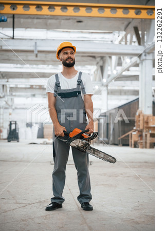 With saw. Industrial worker in wooden warehouse 132262291