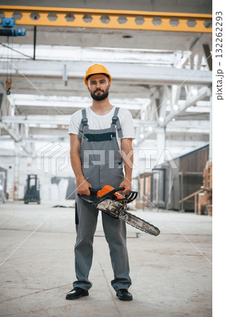 With saw. Industrial worker in wooden warehouse 132262293
