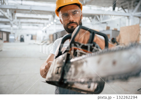 With saw. Industrial worker in wooden warehouse With saw. Industrial worker in wooden warehouse 132262294