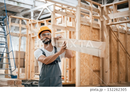 Going and carrying plank. Industrial worker in wooden warehouse 132262305