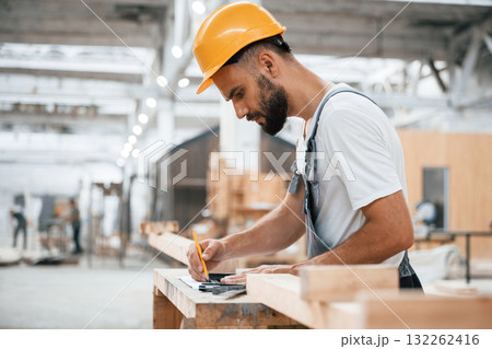 Yellow pen, marks the area. Industrial worker in wooden warehouse 132262416