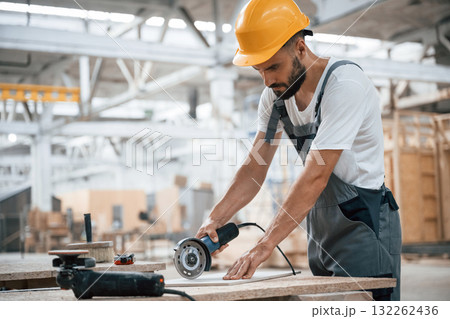 By the table. Industrial worker in wooden warehouse By the table. Industrial worker in wooden warehouse 132262436